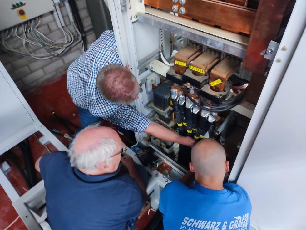 Drei Monteure begutachten die Installation, Blick von oben auf die Köpfe.