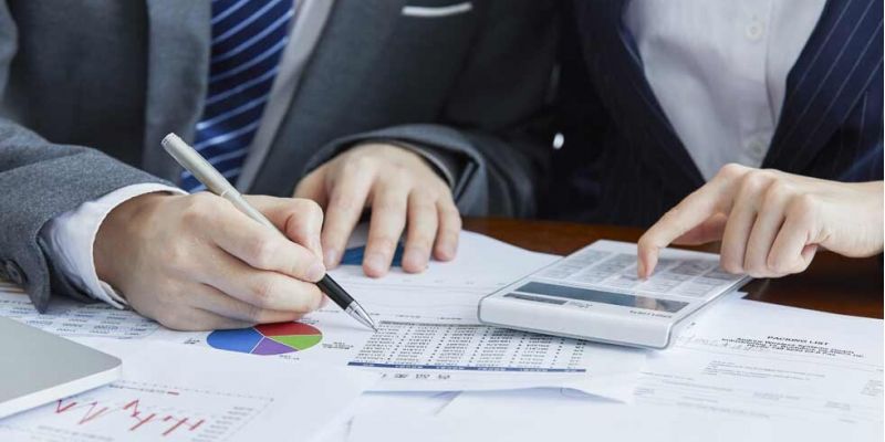 Geschäftsleute in eleganten Anzügen bei einem Meeting mit Unterlagen und Taschenrechner auf dem Tisch